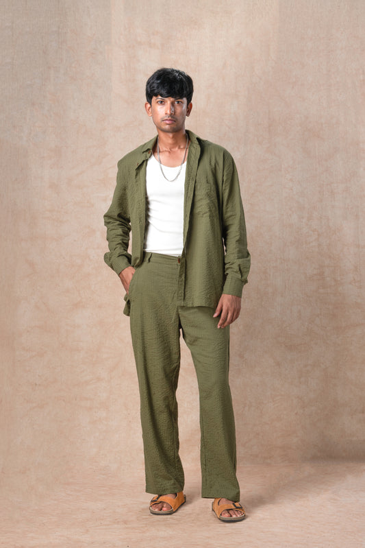 Man wearing a green outfit standing against a beige background